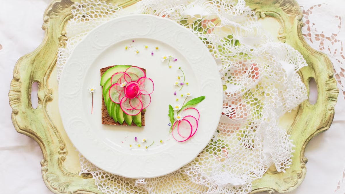 A beautifully plated radish and avocado tartine on a vintage tray with lace accents.