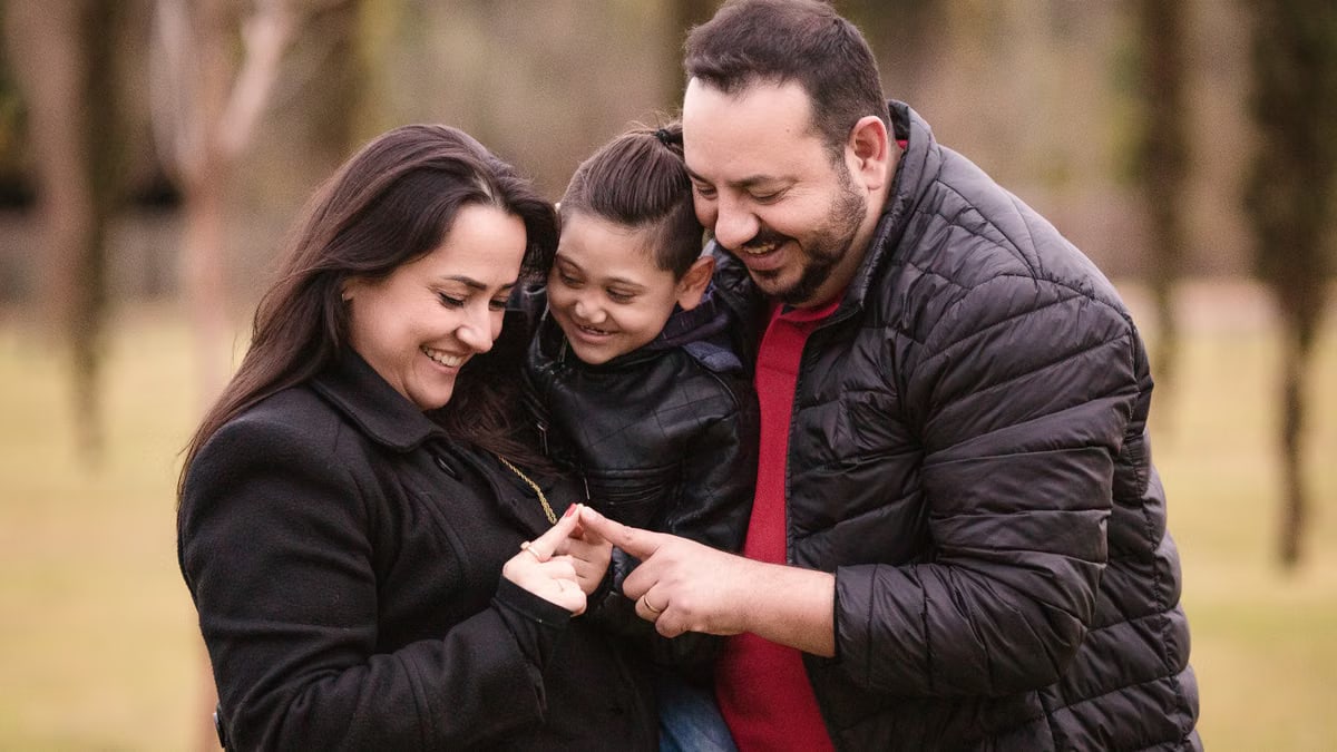 A joyful family of three enjoys a tender moment outdoors, depicting warmth and love.